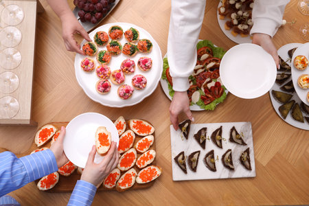 Buffet menu. People taking tasty appetizers from wooden table, top viewの写真素材