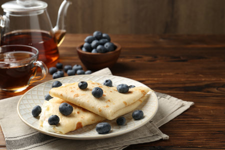 Tasty crepes with cream, blueberries and tea on wooden table, closeupの写真素材
