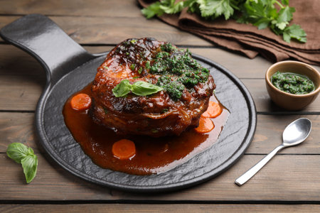 Traditional ossobuco dish with beef steak and sauce served on wooden table, closeupの写真素材