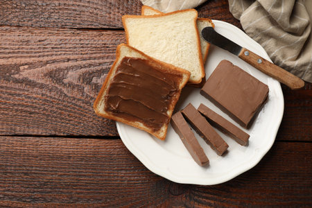 Sandwiches with chocolate butter and knife on wooden table, top view. Space for text