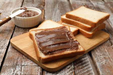 Sandwiches with chocolate butter and knife on wooden table, closeupの写真素材