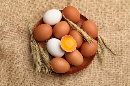 Fresh eggs and spikes on burlap cloth, flat lay