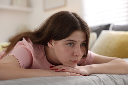 Depressed teenage girl on bed at home