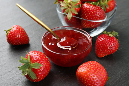 Tasty homemade strawberry jam and berries on black table, closeupの写真素材
