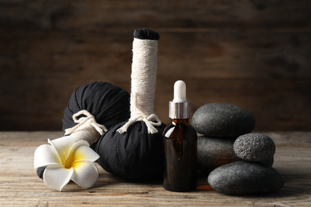 Composition with cosmetic product, spa stones and herbal bags on wooden table, closeupの写真素材