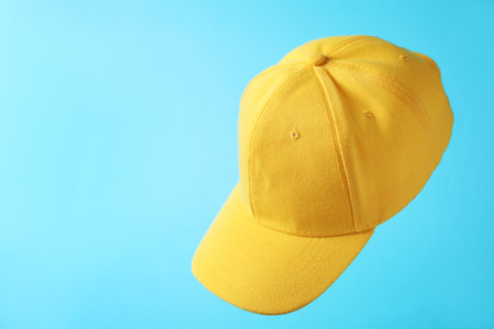 Yellow baseball hat in air on light blue background, space for textの写真素材