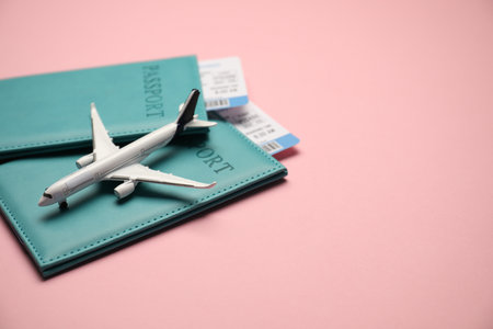 Passports with tickets and airplane model on pink background. Space for textの写真素材