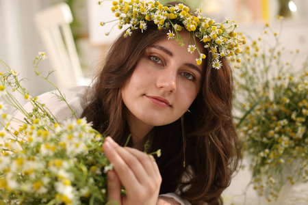 Portrait of beautiful woman with chamomile flowers indoorsの写真素材