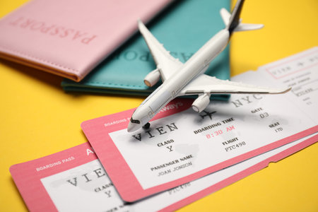 Passports with tickets and airplane model on yellow background, closeup