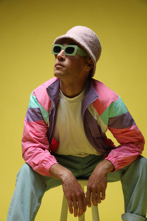 Fashionable portrait of handsome man in stylish outfit on yellow backgroundの写真素材