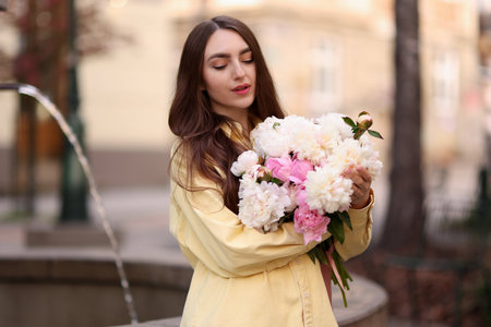 Woman with bouquet of beautiful peonies on city streetの写真素材