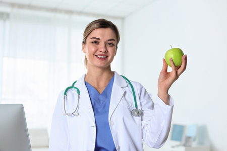 Nutritionist with green apple and stethoscope in clinicの写真素材