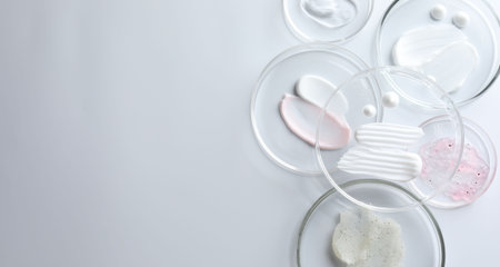 Different cosmetic products in Petri dishes on white background, flat lay. Space for textの写真素材