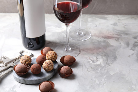 Delicious truffle bonbons and red wine on light gray background. Space for textの写真素材