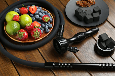 Traditional hookah parts, charcoal cubes, tobacco limes and berries on wooden tableの写真素材