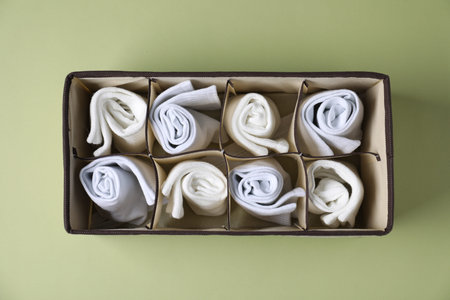 Comfortable white socks in organizer on light green background, top view