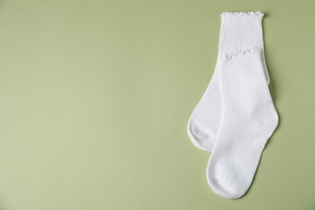 Pair of comfortable white socks on light green background, top view. Space for textの写真素材