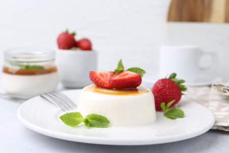 Tasty panna cotta with caramel, strawberries and mint on light table, closeupの写真素材