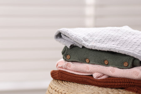 Wool baby clothes on wicker box indoors, closeup. Space for text