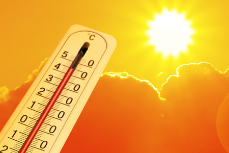 Extremely high temperature on thermometer against orange sky on sunny day. Severely hot summer weatherの写真素材