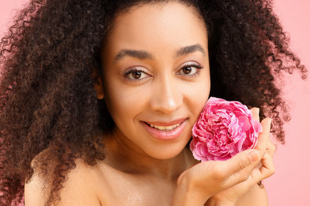 Beautiful Brazilian woman with peony flower on pink background, closeupの写真素材