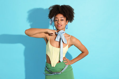 Fashionable portrait of beautiful Brazilian woman in stylish outfit on light blue backgroundの写真素材