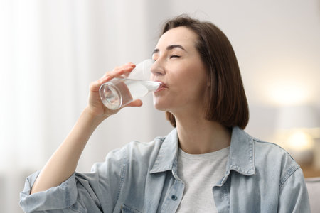 Young woman drinking water from glass at home
