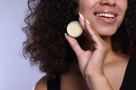 Smiling woman with lip balm on grey background, closeupの写真素材