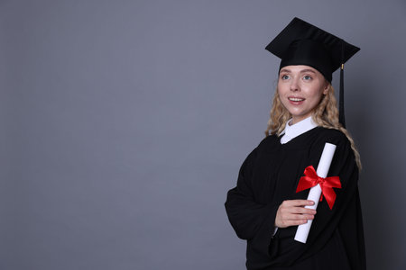 Happy student with diploma after graduation on grey background. Space for textの写真素材