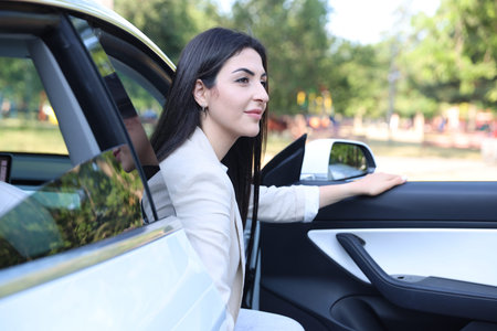 Woman getting out of modern car outdoors