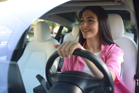 Woman behind steering wheel of modern car, view through windshield