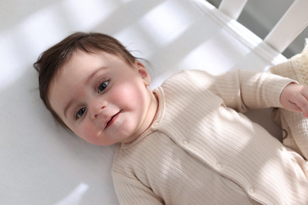 Bedtime. Cute little baby in crib at home, top view