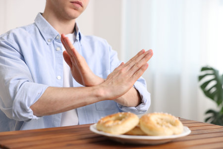 Gluten free diet. Man refusing from pastries at wooden table indoors, closeupの写真素材