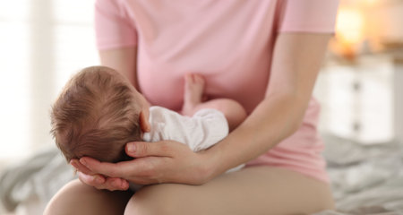 Mom holding her sleeping newborn baby at home, closeup