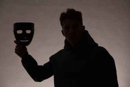 Anonymity. Silhouette of man with mask on grey background