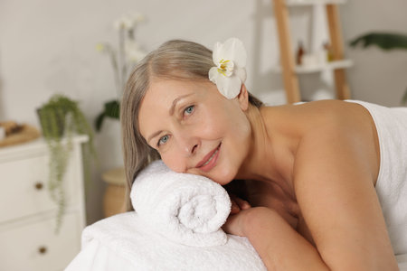 Senior woman relaxing on massage couch in spa salonの写真素材