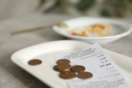 Tips, receipt and dirty plate on grey table in cafe, closeupの写真素材