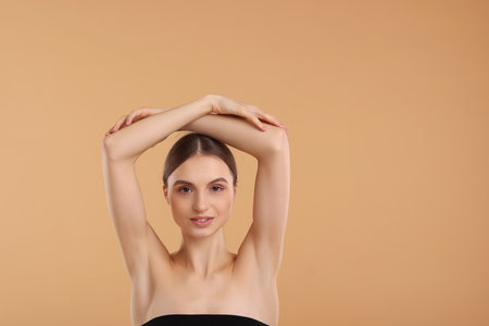 Young woman showing smooth skin after epilation on beige background, space for textの写真素材