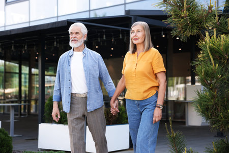 Lovely senior couple walking together near building outdoorsの写真素材