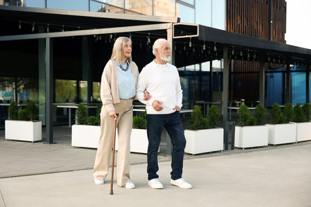 Lovely senior couple walking together near outdoor cafeの写真素材