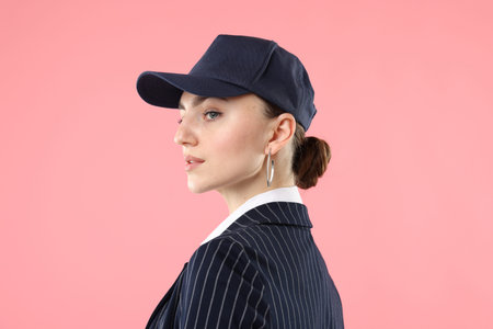 Beautiful woman in stylish baseball hat on pink background