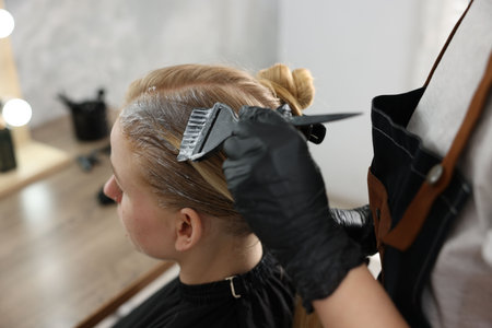 Hairdresser dye applying on woman's hair in salon, closeupの写真素材