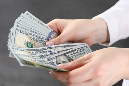 Woman counting dollar banknotes on grey background, closeupの写真素材