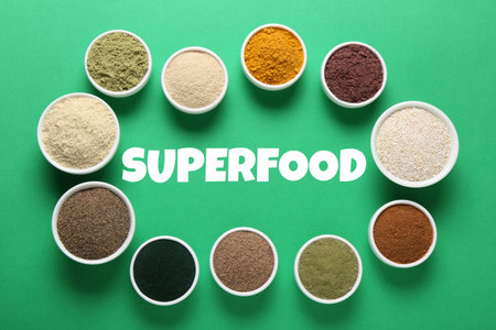 Superfood. Different powders in bowls on green background, flat layの写真素材