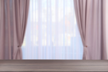 Empty wooden table against window with curtains in roomの写真素材