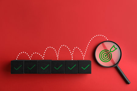 Targeting, business strategy, planning. Black cubes with check marks and magnifying glass with bullseye icon on red background, top viewの写真素材