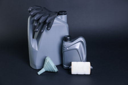Motor oil in plastic canisters, filter, gloves and funnel on dark gray backgroundの写真素材