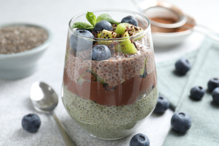 Delicious chocolate pudding with chia seeds, kiwi, mint and blueberries in glass on gray table, closeupの写真素材
