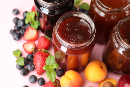 Different jams in jars and ingredients on light pink background, closeupの写真素材