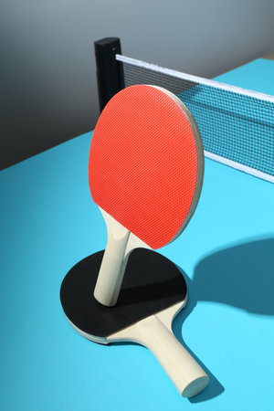 Ping pong rackets and net on light blue tableの写真素材